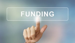business hand clicking funding button on blurred background